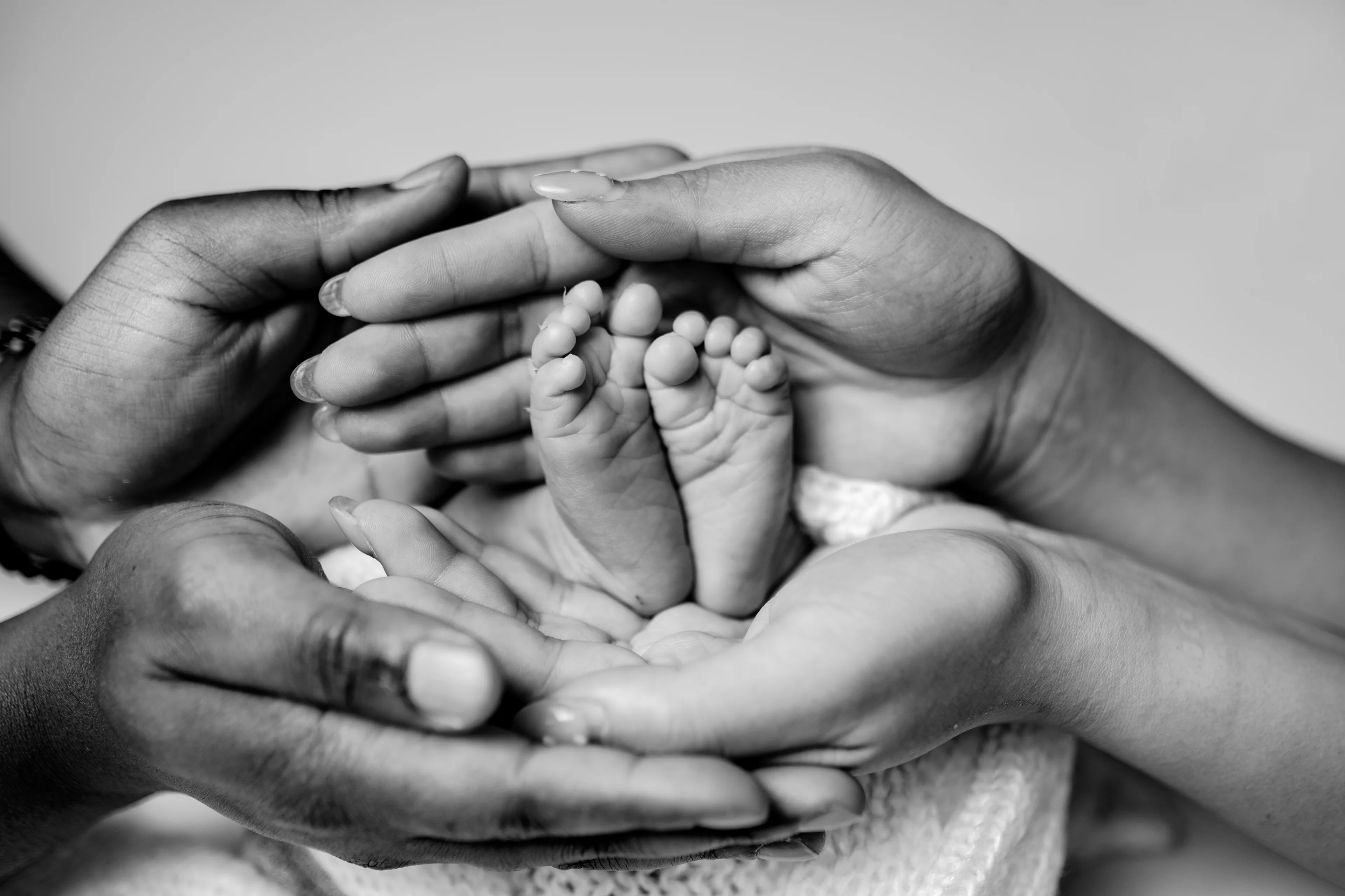 Black-and-white photograph of a newborn's feet cradled in two adult hands
